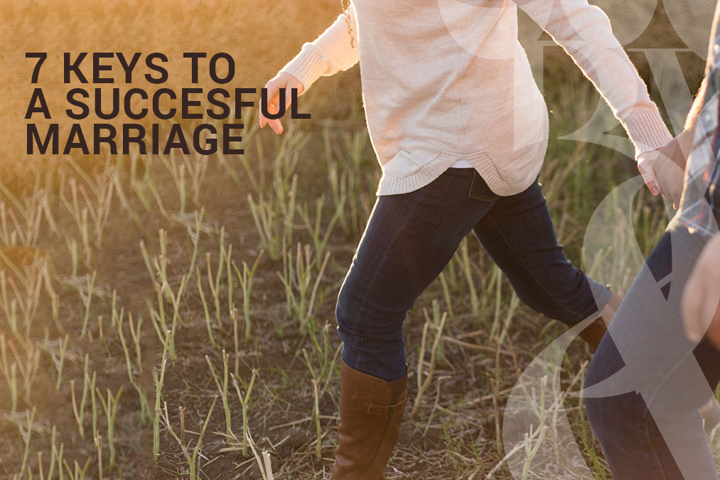 Couple walking hand in hand in a field towards a successful marriage