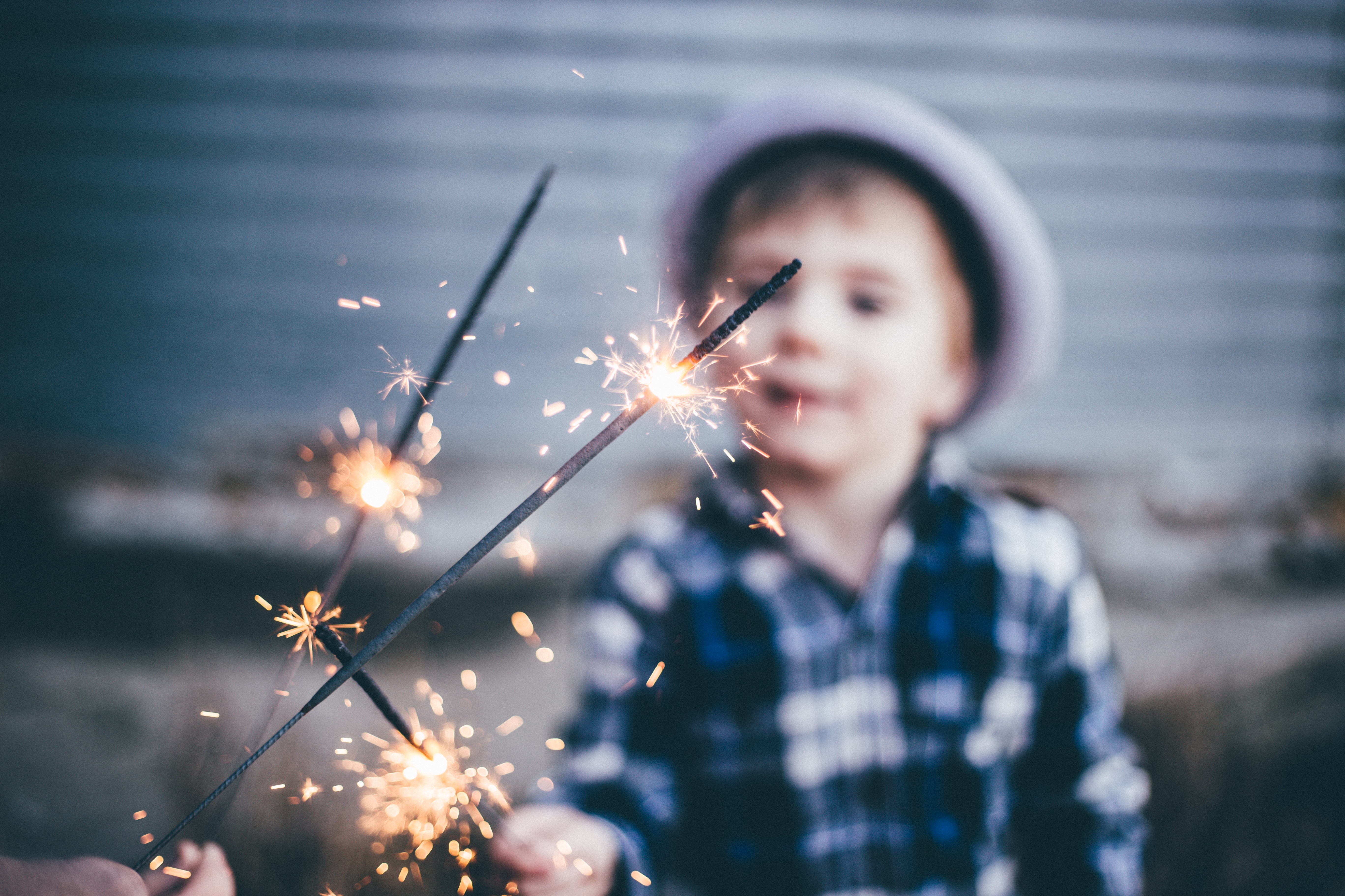 child holding a starlight with a hat on his head wearing a checked navy shirt. He is getting help with his anxiety